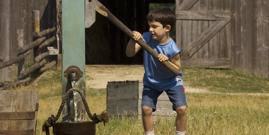 Young boy pulling water well on Oliver Kelley Farm